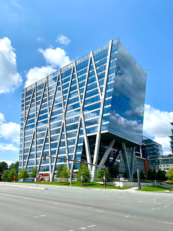 A striking modern office building with a geometric glass facade in an urban setting.